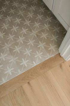 a bathroom floor with white and gray tiles on it's sides, next to a door