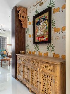 an ornate wooden cabinet in the middle of a room with wallpaper and paintings on the walls