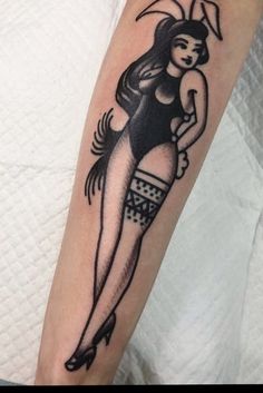 a person with a tattoo on their arm and leg, holding an object in her hand