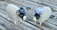 two stuffed sheep wearing hats on top of a wooden table