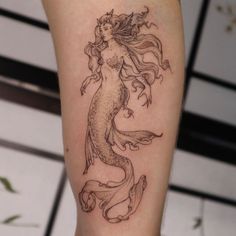 a woman's leg with a mermaid tattoo on the side of her body,