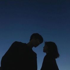 two people standing next to each other under a blue sky with the moon behind them