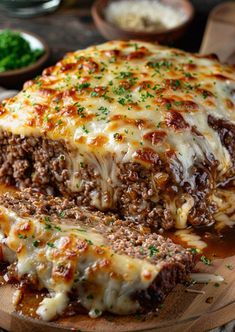 a meatloaf with cheese and sauce on a cutting board next to other food