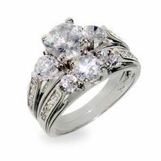 a white gold ring with three diamonds on it's sides and the center surrounded by smaller round stones