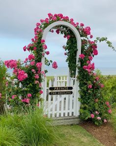 a white gate with pink flowers around it