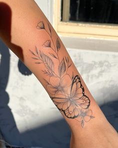 a woman's arm with a butterfly and flower tattoo on the left side of her leg