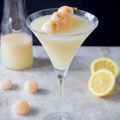 a drink in a martini glass with shrimp on the rim and lemon wedges next to it