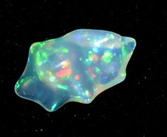 an opalite is shown against a black background with white and green dots on it