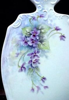 a white vase with purple flowers painted on it