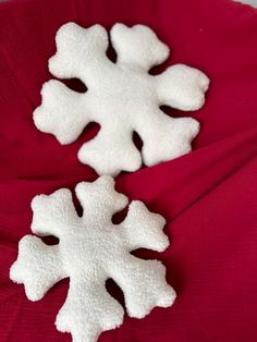 two snowflakes sitting on top of a red cloth