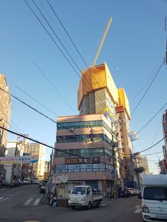 a large building under construction on the corner of a street with cars parked in front of it