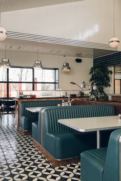 the interior of a restaurant with green booths and black and white floor tiles on the walls