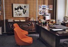 an orange chair sits in front of a wooden desk