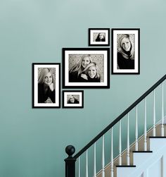 black and white photo frames hanging on the wall next to a stair case in a home