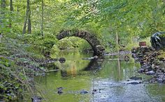 an old stone bridge over a stream in the woods