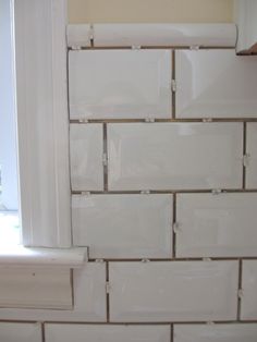 a white tile wall with some windows in it and a window sill on the other side