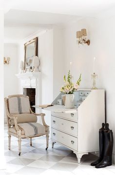 a living room with white furniture and flowers in vases on top of the dresser