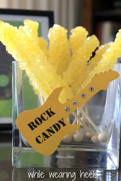 rocks and candy in a glass vase on a table with a guitar shaped sign that says rock candy