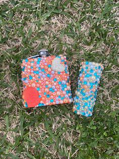 two flasks are laying on the grass with hearts and bubbles painted on them