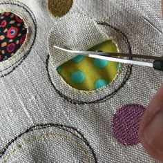 someone is using scissors to sew on the fabric with different colors and shapes in it