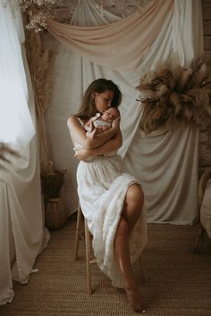 a woman sitting on a chair holding a baby