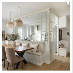 a dining room table with chairs and a bench in front of the door that leads to an open kitchen