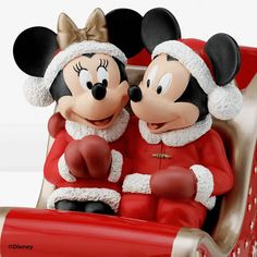 two mickey and minnie mouse figurines sitting in a sleigh