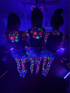 three girls are standing in the middle of a room with neon lights on their body