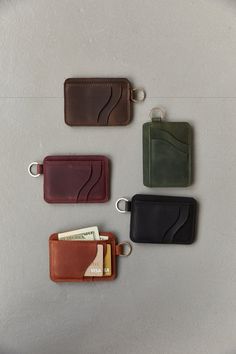 four different colored leather wallets sitting next to each other on top of a table