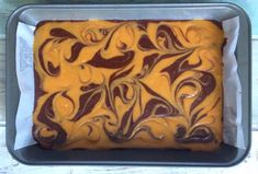 a cake in a pan with chocolate swirls on the top and yellow icing