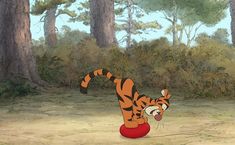 the tigger from winnie the pooh is playing with a ball in front of some trees