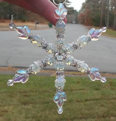 a glass snowflake hanging from the side of a red pole in front of a road