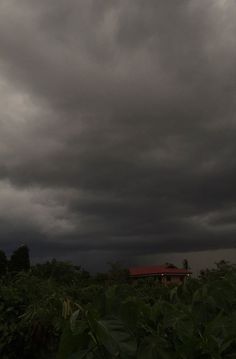 dark clouds loom over a farm house in the distance