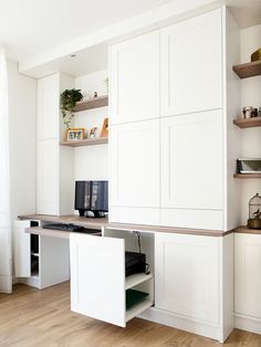 an office with white cupboards and wooden flooring, including a computer on the desk