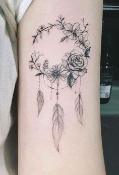 a woman's arm with a rose and feathers tattoo on the left side of her arm