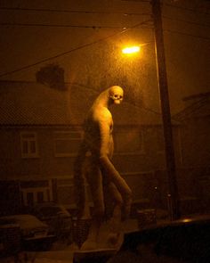 a creepy figure is walking in the rain at night