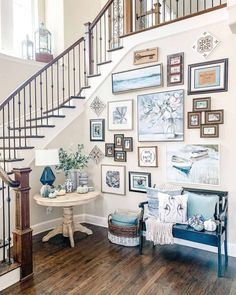 a living room filled with furniture and framed pictures on the wall next to a stair case