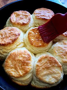 a red spatula being used to stir biscuits in a skillet