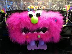 a pink furry monster head sitting on top of a black counter next to a mirror