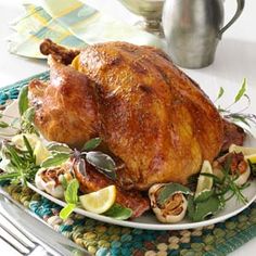 a roasted turkey on a platter with lemons and herbs