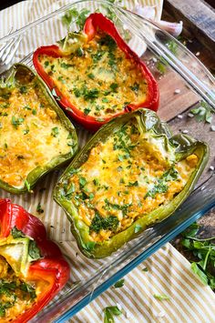 four stuffed peppers sitting on top of a glass pan filled with cheese and veggies