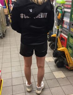 a woman is standing in the middle of a store aisle with her back to the camera