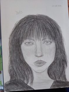 a pencil drawing of a woman's face with long hair and bangs on paper