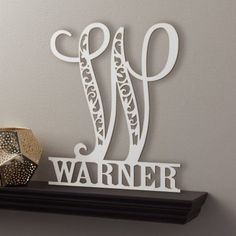 a wooden sign that says w is for warr on top of a shelf next to a candle