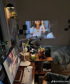 a computer desk with a monitor, keyboard and mouse on it next to a bed