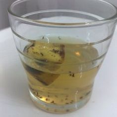 a glass filled with liquid sitting on top of a white table next to a window