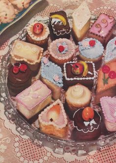 there are many small cakes in the glass plate on the table and one is decorated with icing