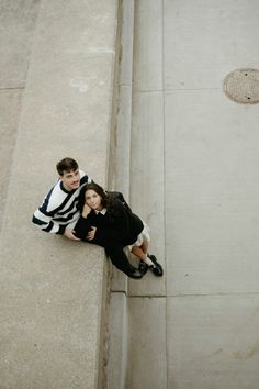 a man and woman sitting on the side of a building