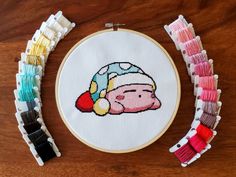 a cross - stitch pattern with a pig wearing a santa hat on it next to some colorful thread spools