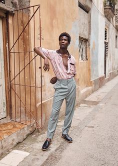 a man standing on the side of a road next to a building and holding his arm out